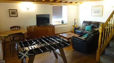 a living room with a table with a video game at Blaentwrch Farmhouse in Llanddewi-Brefi