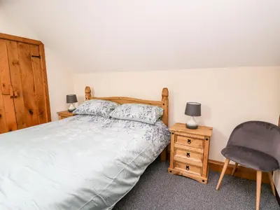 a bedroom with a bed and a chair at Ploony Barn in Bleddfa