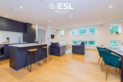 a kitchen and living room with a counter and chairs at Modern 2 Bedroom Church Apartment 5 Mins to Town Centre - Free Parking in Shrewsbury