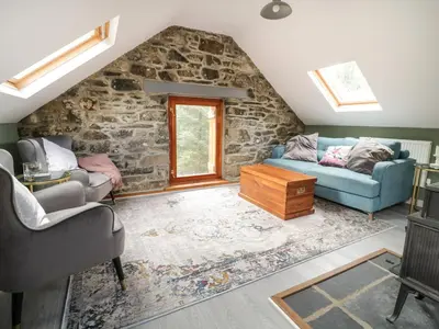 a living room with two couches and a stone wall at Brithgwm Canol in Dolgellau