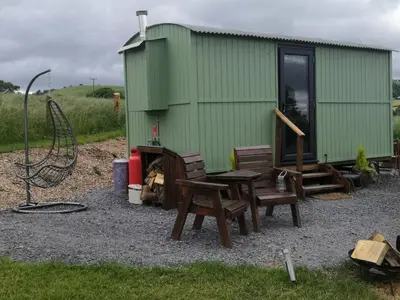 a green building with chairs and a table in front of it at Y Cwtch in Trefeglwys