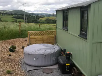 a green house with a bed and a ottoman next to it at Y Cwtch in Trefeglwys