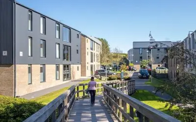 a person walking down a bridge near a building at Fferm Penglais Apartments in Aberystwyth