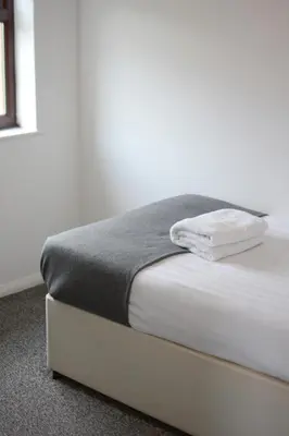 a white bed with a gray blanket on top of it at 2 bed house, walking distance Shrewsbury centre in Shrewsbury