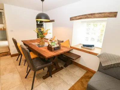 a dining room with a wooden table and chairs at Bwthyn Bach Gwyn in Penrhyndeudreath