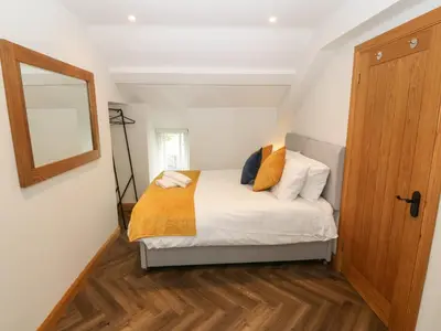 a bedroom with a bed and a mirror on the wall at Bwthyn Bach Gwyn in Penrhyndeudreath