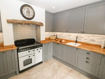a kitchen with gray cabinets and a white stove top oven at Bwthyn Bach Gwyn in Penrhyndeudreath