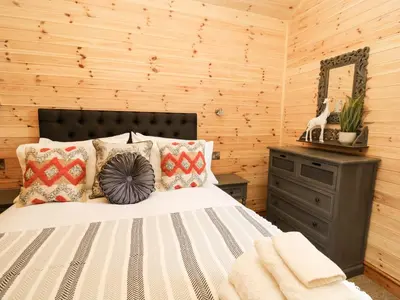 a bedroom with a bed and a wooden wall at The Larches in Llanidloes