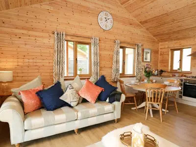 a living room with a couch and a clock on the wall at The Larches in Llanidloes