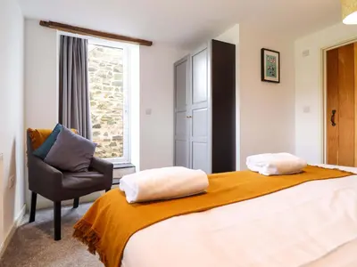 a bedroom with a bed and a chair and a window at Bwthyn Y Bugail Shepherd's Cottage in Oswestry
