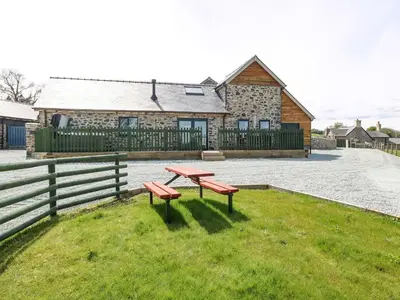 a picnic table in the grass in front of a house at Y Granar The Granary in Oswestry
