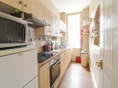 a kitchen with white cabinets and a white microwave at The Nook in Tywyn
