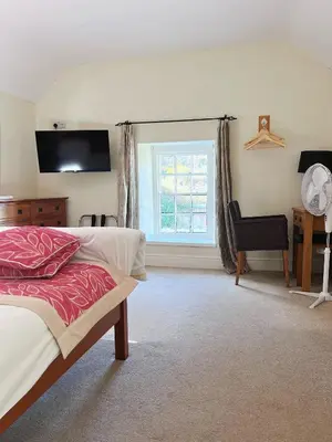 a bedroom with a bed and a window and a desk at The Crown Hotel in Corwen