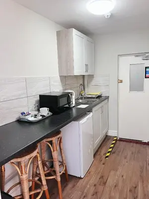 a kitchen with a counter with stools and a microwave at The Crown Hotel in Corwen