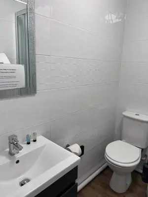 a white bathroom with a toilet and a sink at The Crown Hotel in Corwen