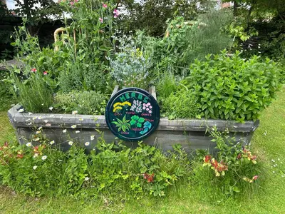 a garden with a sign in the middle of some plants at Milkwood Cottage in Corwen