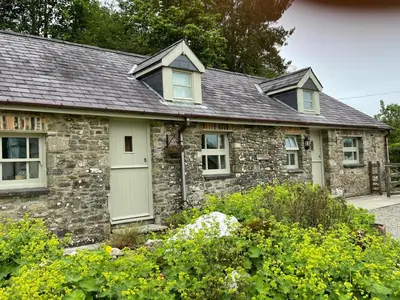 a stone house with a gray roof and windows at Crug Yr Eryr Isaf in Llandysul