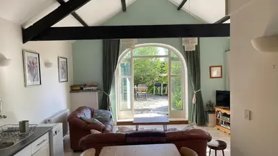 a living room with two couches and an open door at Crug Yr Eryr Isaf in Llandysul