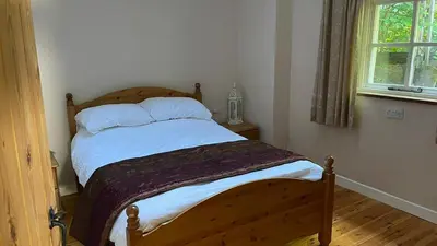 a bedroom with a wooden bed with white sheets and a window at Crug Yr Eryr Isaf in Llandysul