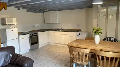 a kitchen with white cabinets and a wooden table at Crug Yr Eryr Isaf in Llandysul