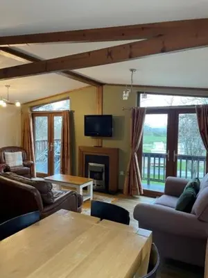 a living room with couches and a table and a tv at The Oak Lodge in Aberystwyth