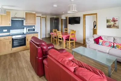 a living room with a red couch and a table at The Pine Lodge in Aberystwyth