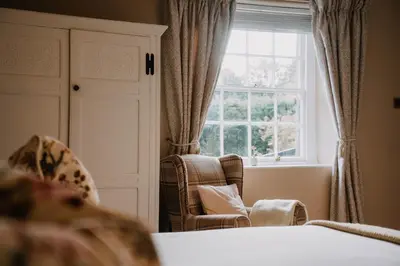 a bedroom with a bed and a window and a chair at Three Cocks Hotel in Brecon