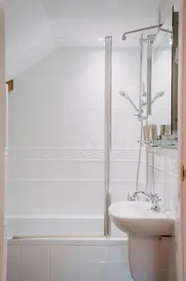 a white bathroom with a shower and a sink at Three Cocks Hotel in Brecon