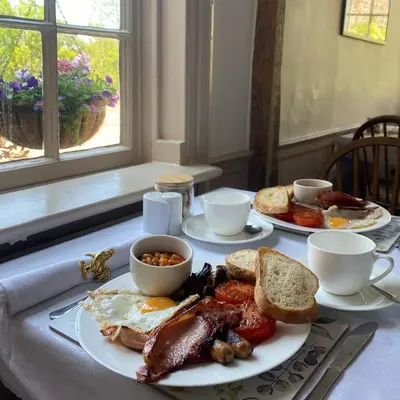 a breakfast table with eggs bacon and toast and coffee at Three Cocks Hotel in Brecon