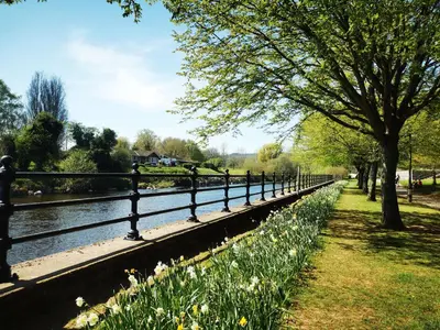 a fence next to a body of water with flowers at Kooky Cottage in Brecon