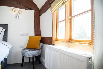a bedroom with a window and a chair next to a radiator at The Yew Tree Inn in Church Stretton
