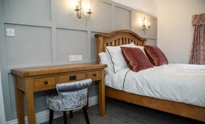 a bedroom with a bed with a desk and a chair at The Yew Tree Inn in Church Stretton