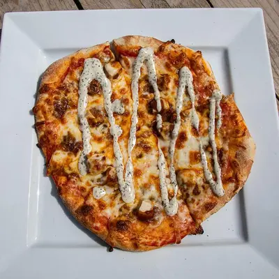 a pizza on a white plate on a table at The Yew Tree Inn in Church Stretton
