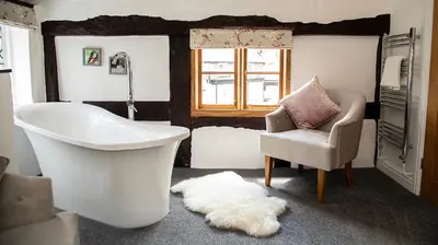 a bathroom with a tub and a chair and a window at The Yew Tree Inn in Church Stretton