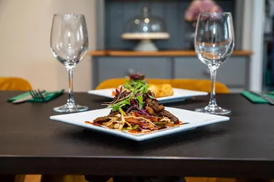 a plate of food on a table with two wine glasses at The Yew Tree Inn in Church Stretton