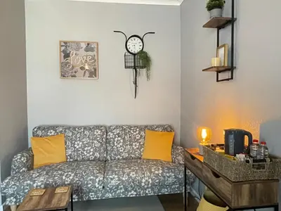 a living room with a couch and a clock on the wall at Westend Holiday Room 4 Brecon in Brecon