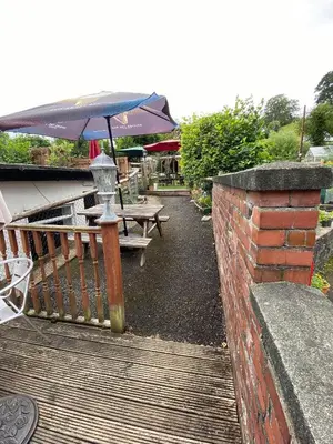 a patio with an umbrella and a table and benches at Old New Inn, Llanfyllin in Llanfyllin