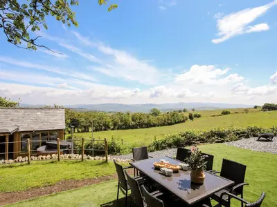 a table and chairs on a patio with a view at Hafotty Gelynen in Corwen