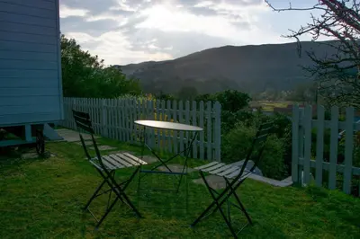 a table and chairs on a yard with a fence at Hilltop Hut in Church Stretton