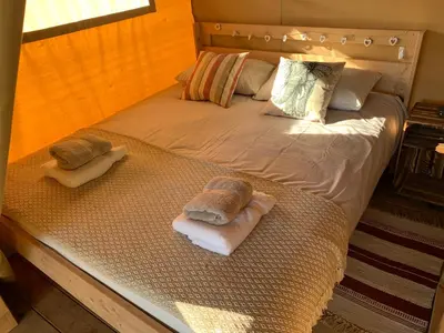 a bed with two towels and pillows on it at Safari Tent with Hot Tub in heart of Snowdonia in Dolgellau