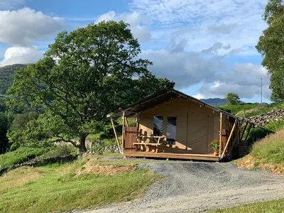 a cabin on a dirt road in a field at Safari Tent with Hot Tub in heart of Snowdonia in Dolgellau
