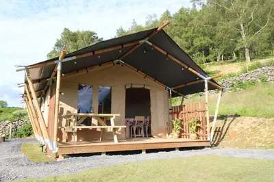 a tent with a black roof on a field at Safari Tent with Hot Tub in heart of Snowdonia in Dolgellau