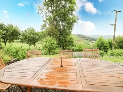 a wooden table with two chairs sitting around it at Pant Y Rhedyn in Llandrindod Wells