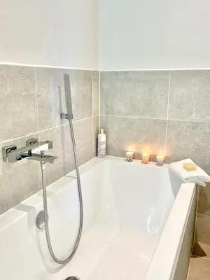 a white bath tub in a bathroom with candles at Apartment Twelve in Shrewsbury