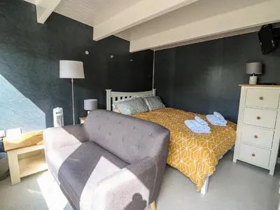 a bedroom with a bed and a couch and a chair at Caban Glas in Aberystwyth