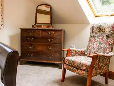 a dresser and a chair in a room with a mirror at Pool Barn in Craven Arms