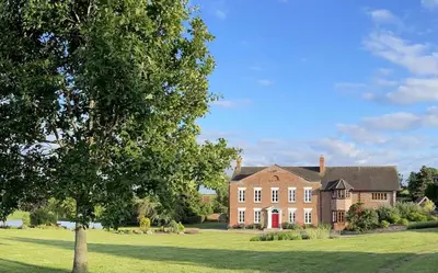 a large brick house with a tree in front of it at Winsley Park Farm in Leominster