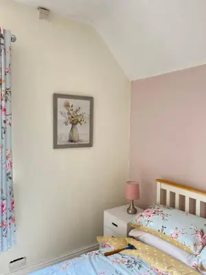 a bedroom with a bed and a vase of flowers on the wall at Ravelstone in Church Stretton