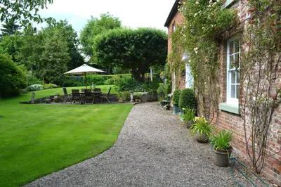 a garden with a table and an umbrella next to a building at The Old Vicarage in Shrewsbury
