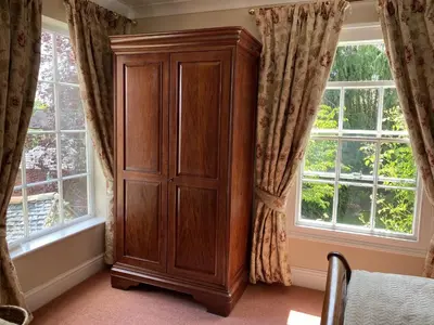 a wooden cabinet in a room with two windows at The Old Vicarage in Shrewsbury